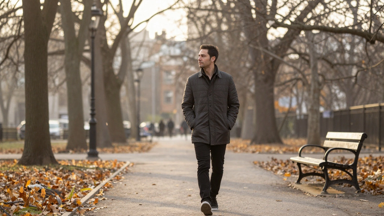 Мужчина гуляет в парке осенью, один, без телефона, среди опавших листьев.