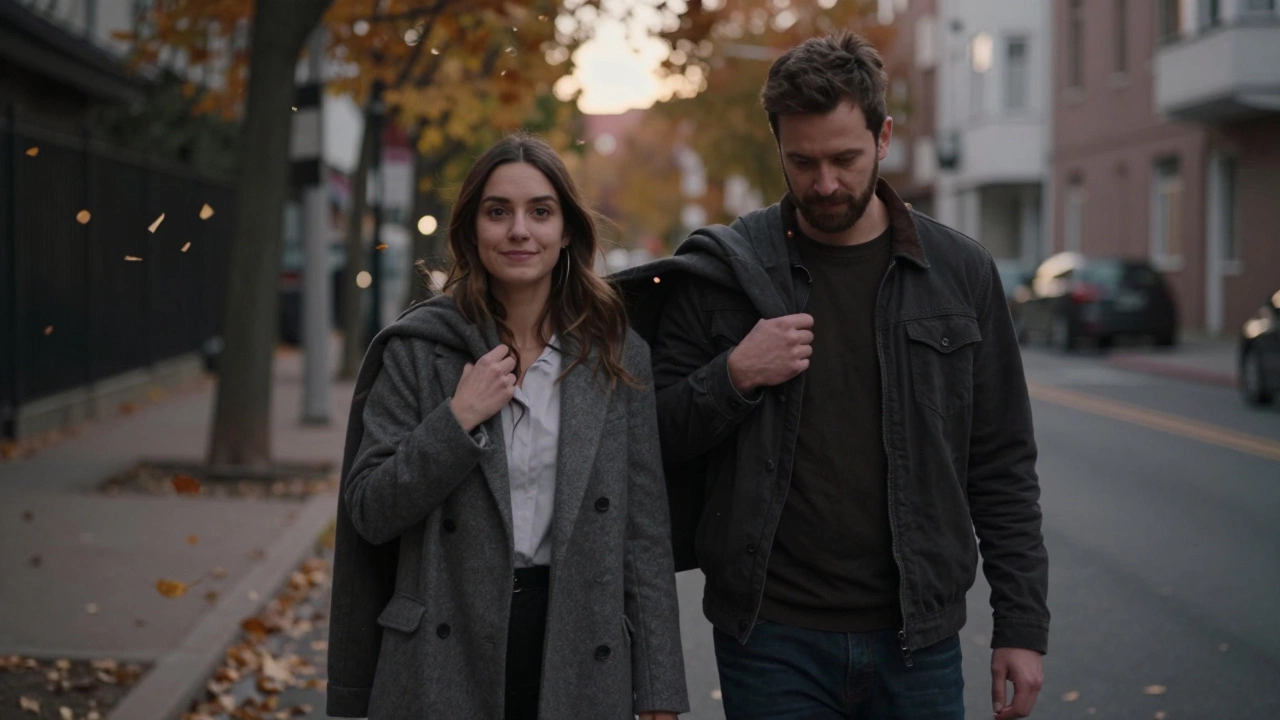 Мужчина молча накидывает куртку на плечи женщины, они идут по улице при закате.